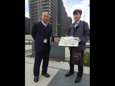 Akio Kajiyama (left) and Hideki Kiso, deputy directors at the Urban Redevelopment Section, Tokyo Metropolitan Government at the Olympic Village with a booklet with images of the finished smart city.