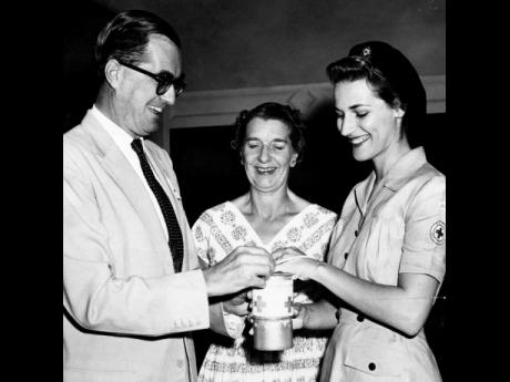 February 14 1959 – With a smile, Governor Sir Kenneth Blackburne and Lady Blackburne buy their tags for Red Cross Day from Mrs Maurice Facey of the Jamaica Red Cross Society at King’s House. 