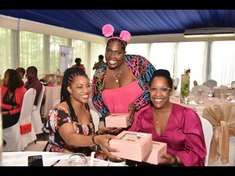 Lifestyle reporter Krysta Anderson (centre) presents cupcakes to Kayon Mitchell (left), Flow Jamaica’s director of corporate affairs, and Nyree Coke, Flow Jamaica’s director of customer experience, during Monday’s luncheon.