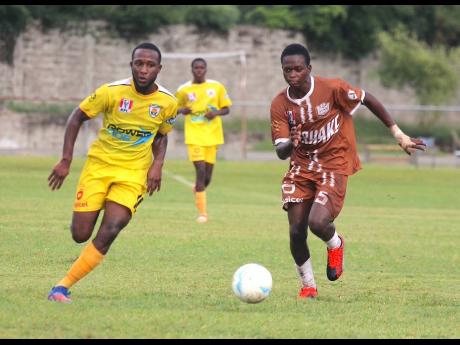 Garvey Maceo’s Cleo Clarke (left) in a foot race with Central High’s Emory Ayton during their round-of-16 ISSA daCosta Cup clash at Foga Road yesterday.
