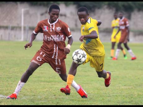 Central High defender Emory Ayton (left) chases the Garvey Maceo’s Christopher Mundle during their ISSA daCosta Cup Zone A round-of-16 clash at Foga Road yesterday.