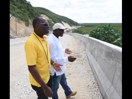 Everald Warmington (right), minister without portfolio in the Ministry of Economic Growth and Job Creation, touring a section of the road under construction in Grants Pen, St Thomas Western, on Wednesday with Stephen Shaw, manager of communication and cust