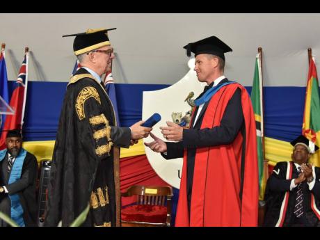 
The University of the West Indies (UWI) bestowed the Honorary Degree of Doctor of Laws (LLD) on businessman Adam Stewart (right) for his work as an entrepreneur and a philanthropist during its graduation ceremony yesterday. Here he is being presented with