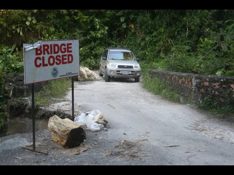 A motorist defies warning signs to drive across the dilapidated Woodsville Bridge that has been closed by both the National Works Agency and the Hanover Municipal Corporation. 