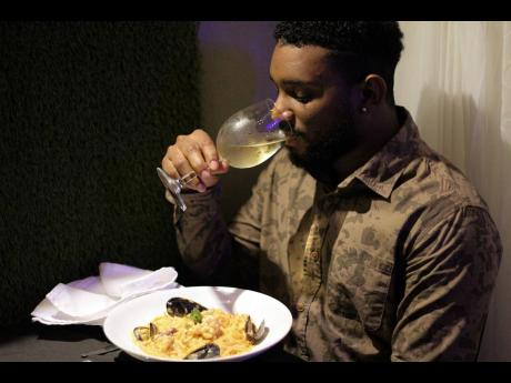 Delano ‘DJ3D’ Thomas takes a sip of Pinot Grigio before getting his taste  buds tangled with Trio’s creamy Tuscan seafood medley with linguine pasta dish.  