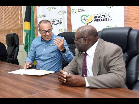 Health and Wellness Minister Dr Christopher Tufton (left) and Dr Neville Graham, CEO of Winchester Surgical and Medical Institute, have dialogue during a signing ceremony for Project Code Care at the health ministry’s New Kingston headquarters on Thursda