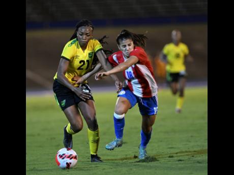 Jamaica’s Cheyna Matthews (left) dribbles past Paraguayan player Camila Arrieta during last night’s friendly international match at the National Stadium. Paraguay won 2-1. 