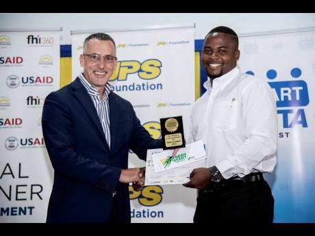 Rohan Campbell receives the award for Top Performer in Electrical Installation from JPS president and CEO, Michel Gantois.