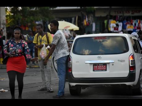 A taxi operator solicits a passenger at South Parade in downtown Kingston Tuesday, a day after many had withdrawn their services to press for a traffic ticket amnesty. 