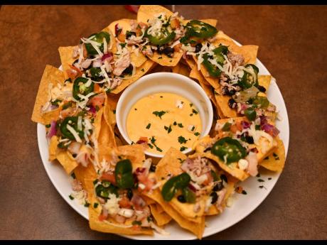 Loaded chicken nachos: tortilla strips, layered with shredded chipotle chicken, blackbeans, white jalapeno queso, pico de gallo, fresh jalapenos, Jack cheese and cilantro.