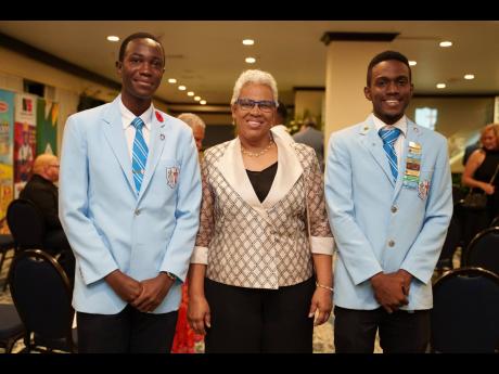 Ushers from St George’s College sixth form Nathan Crosdale (left), deputy head boy, and Maliek Harris (right), Student Council president, flank Margaret Campbell, principal of St George’s College.