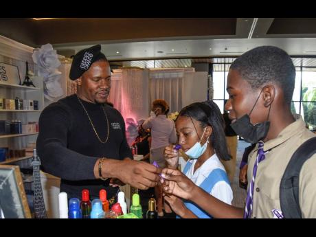 Andrew Clarke, a representative of  T. Geddes Grant, allows Christen Senior (centre), a third form student of Ardenne High, to sample a fragrance dubbed Abstract Art, and Tevon Thomas, a fifth form student of Kingston College, to sample the Pink Neon Fragr