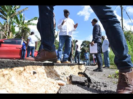 Everald Warmington, minister responsible for works, talks with officials during a tour of St Ann South Western Wednesday to assess damaged roads and bridges. 