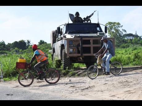 Two farmers pass a military armoured vehicle stationed at an access point along the Bernard Lodge main road, where movement was restricted during a demolition exercise in October. 