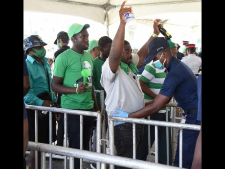 Jamaica Labour Party supporters are searched by a policeman before entering the National Arena for the party’s 79th annual conference on Sunday.