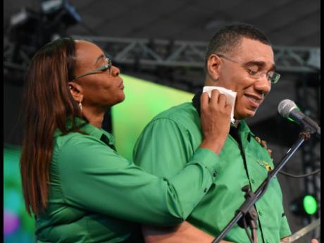 Juliet Holness, member of parliament for St Andrew East Rural, wipes sweat from her husband Prime Minister Andrew Holness’ face while he delivered his address at the Jamaica Labour Party’s 79th annual conference Sunday. 