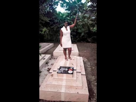Camese Wright, degree in hand, stands on the grave of her mother , Janice Williams.