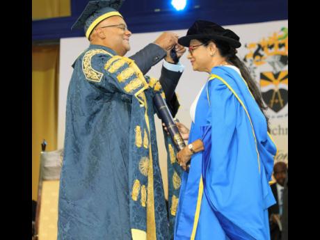 UTech, Jamaica Chancellor Lloyd Carney (left) adjusts the tassels of Dr Jacquiline Bisasor-McKenzie, CD, Chief Medical Officer, Ministry of Health and Wellness, during her conferment of the Doctor of Medicine, Honoris Causa, at the UTech, Jamaica Ceremony 