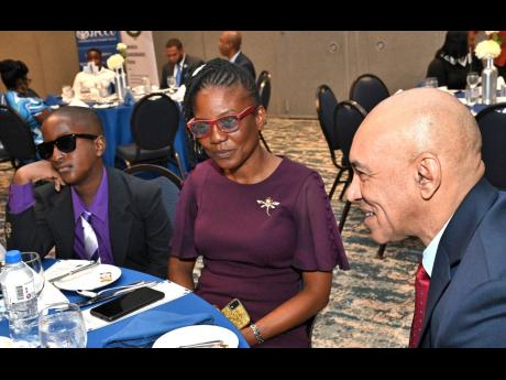 Police Commissioner Major General Antony Anderson (right) having a chat with Josephine Parker-Mullings, widow of Corporal Oliver Mullings, and her son Oliver Mullings at the Commissioner’s Luncheon for Children of Fallen Officers at The Jamaica Pegasus h