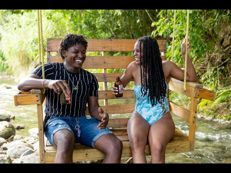 Graphic designer Antonio Mundell (left) and Danielle Insang sipped on ice-cold Red Stripe beers as they enjoyed the low tide and good vibes at Twin Rivers.