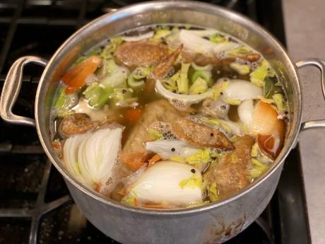Vegetables and turkey parts cook on a stove to make turkey stock.