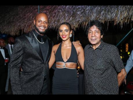 From left: Asafa Powell and wife, Alyshia, pose with Kenny Benjamin, executive chairman  of the Guardsman Group.