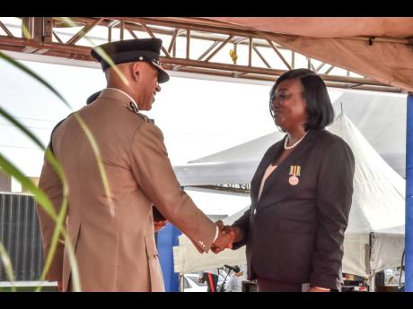 Police Commissioner Major General Antony Anderson congratulates Sergeant Annetta Newell from the Kingston Western division on being awarded the JCF Medal of Honour for Long Service during a ceremony at the Police Officers’ Club on Hope Road in St Andrew 