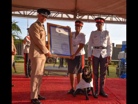 From left: Commissioner of Police Major General Antony Anderson hands Constable Britanny Simpson a citation in honour of retiring service dog Chad as Constable Shavar Manning looks on during the JCF Long Service and Good Conduct Awards Ceremony on Thursday