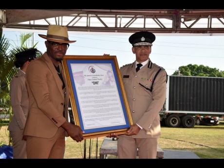 Commissioner of Police Major General Antony Anderson (right), presents entertainer Omar ‘OMI’ Pasley, a former member of the Jamaica Constabulary Force, with a citation in his honour at the JCF Long Service and Good Conduct Award Ceremony on Thursday.