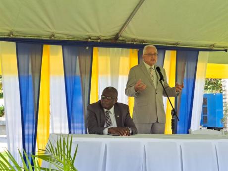 Justice Minister Delroy Chuck addresses the Legal Aid Council’s Justice Fair at the Harmony Beach Park in Montego Bay, St James, on Friday, November 25. Seated is Bishop Conrad Pitkin, custos of St James.