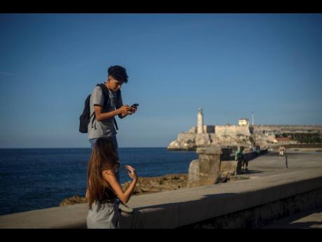 A youth uses his smartphone during a walk along the Malecon seawall in Havana, Cuba, last Friday. Ever-widening access to the Internet is offering a new opportunity for Cubans looking for hard-to-obtain basic goods.