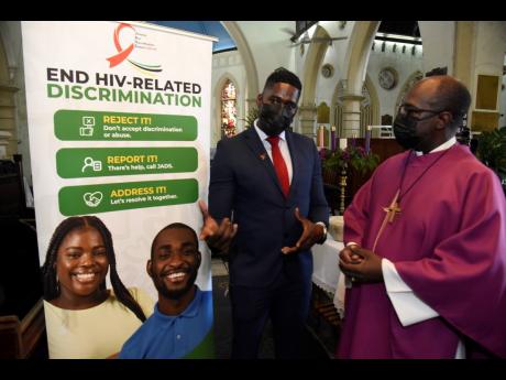 Father Claude Campbell (right) listens as Jumoke Patrick, executive director of the Jamaican Network of Seropositives, talks about the anti-discrimination campaign after the World AIDS Day service at St Andrew Parish Church in Half-Way Tree on Sunday.