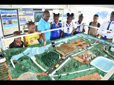 Students from various schools look on as Acting Commercial Manager at the National Irrigation Commission, Kenroy Hare outlines the workings of an irrigation model on display during the Minard Livestock Show and Beef Festival at Minard Estate, in Brown’s