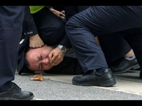 Policemen pin down and arrest a protester during a protest on a street in Shanghai, China. Authorities eased anti-virus rules in scattered areas but affirmed China’s severe ‘zero- COVID’ strategy Monday after crowds demanded President Xi Jinping resi