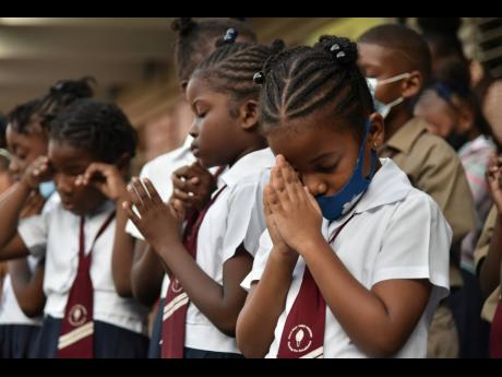 Half-Way Tree Primary School pupils bow their heads in prayer during Monday morning’s special devotion after three students were injured in a crash in the St Andrew capital last Friday.
