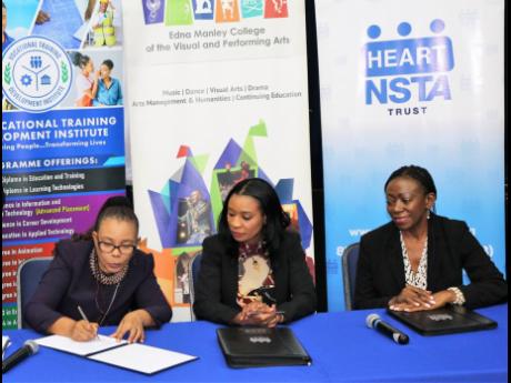 Interim principal at the Edna Manley College of the Visual and Performing Arts, Dorrett Campbell (left), signs the memorandum of understanding between the college and the HEART/NSTA Trust, as Dr Taneisha Ingleton (centre), managing director of the HEART/NS