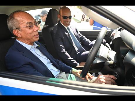 Major General Antony Anderson (right), commissioner of police, and Dr Horace Chang, minister of national security, tests one of the 15 new Mitsubishi L200 pickups and 10 Toyota Hilux pickups which were handed over to the Office of the Commissioner of Polic