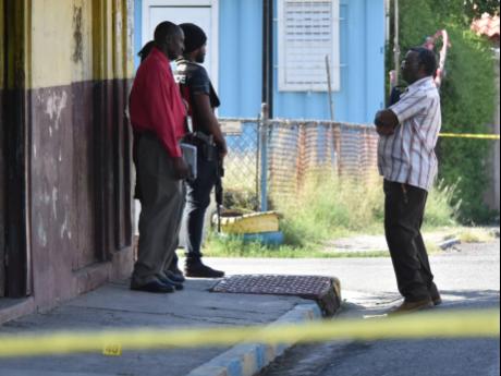 Police personnel man a crime scene in Hannah Town, west Kingston, on Tuesday. Two men were killed in a drive-by attack. 