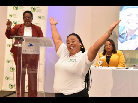 Kayshia Kerr (left), CEO of the National Parenting Support Commission, announces Nicole Ramsay (foreground) as the top parent mentor for the organisation in Jamaica while Anita Bailey, community relations education officer in the Mandeville office of the M