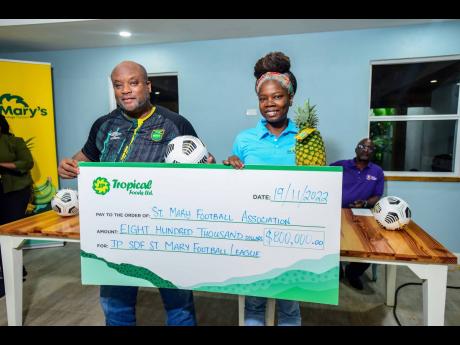 JP Farms marketing executive Gayon Douglas presents St Mary Football Association President James Pearson with a symbolic cheque valued at $800,000 to solidify JP Farms’ sponsorship of the association during a launch on Saturday, November 19 at the JP Far