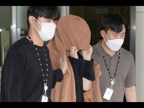A woman (at centre) leaves the Seoul Central District Prosecutors’ Office at Ulsan Jungbu Police Station in Ulsan, South Korea, on September 15. A South Korean court has approved the extradition of the 42-year-old woman facing murder charges in New Zeala