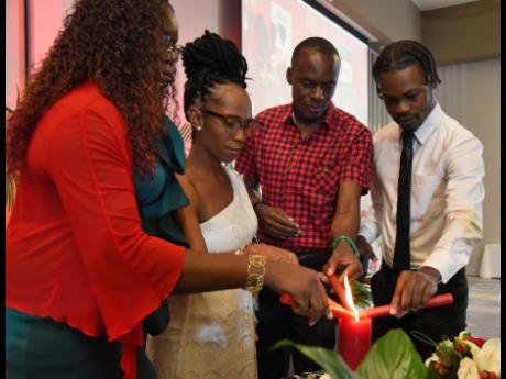 Community facilitators (from left) Francine Morgan, Antonette Burns, Ryan McKenzie, and Nikoy Henry participate in a candlelighting session of the Jamaica Network of Seropositives (JN+) World AIDS Day breakfast forum at AC Hotel in Kingston on Wednesday. 