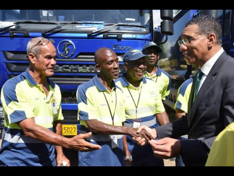 Prime Minister Andrew Holness (right) meets some of the drivers of the new garbage trucks during a handover ceremony at National Heroes Park on Wednesday. Fifty new trucks deployed by the National Solid Waste Management Authority are expected to boost garb