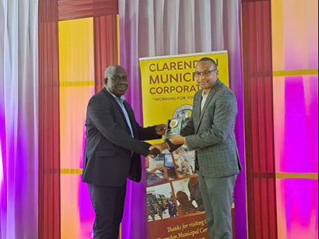 Baldvin McKenzie, Clarendon Parish Manager of the Social Development Commission receives an award on behalf of the agency from CEO of the Clarendon Municipal Corporation, Rowhan Blake.