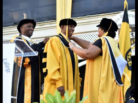 Educator Hugh Morris (centre) is bestowed with an honorary doctorate by Mico University College President Dr Asburn Pinnock (left) and Vice-President Dr Kay Dunkley on Thursday. Island Grill restaurateur Thalia Lyn was also conferred with an honorary degre
