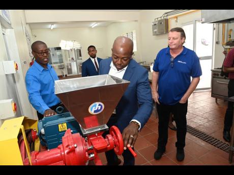 Milbert Miller, (left) principal of Sydney Pagon STEM Academy, shows one of the processing machines to (from second left) Jeremain Brown, chairman of Sydney Pagon STEM Academy, Pearnel Charles Jr., minister of agriculture and fisheries and Jean-Philippe Be