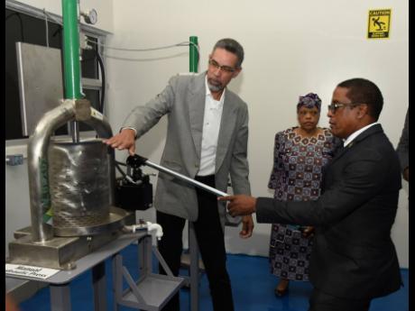 David Harrison (left), director of the Jamaica Business Development Corporation (JBDC), explains the use of the manual hydraulic press to Dr Norman Dunn (right), state minister in the Ministry of Industry, Investment and Commerce, at Friday’s opening of 