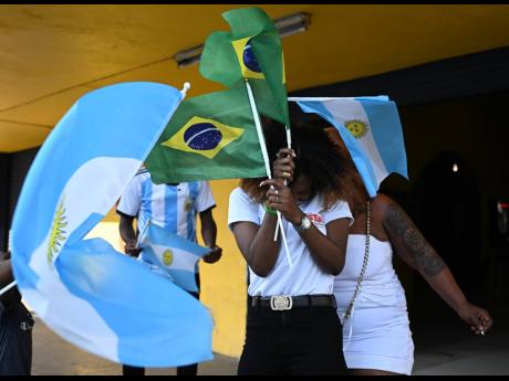 A Brazil supporter is sandwiched between two Argentina supporters during the Argentina vs Poland FIFA World Cup match on November 30. 