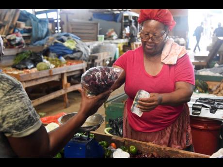 Irene Brown Phillips sells a pound of sorrel from her stall in Coronation Market, downtown Kingston. Up to the last week of November, Phillips said that sorrel sales were lagging expectations. 