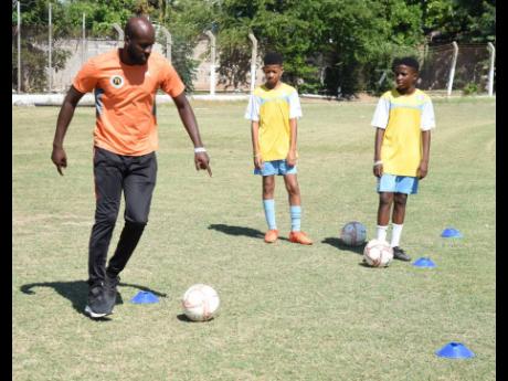 Raymond Leveridge, coach of the St George’s College under-14 football team, demonstrates a few football drills to players Dejan Ho-Young (centre) and Ryland Fray-Campbell.